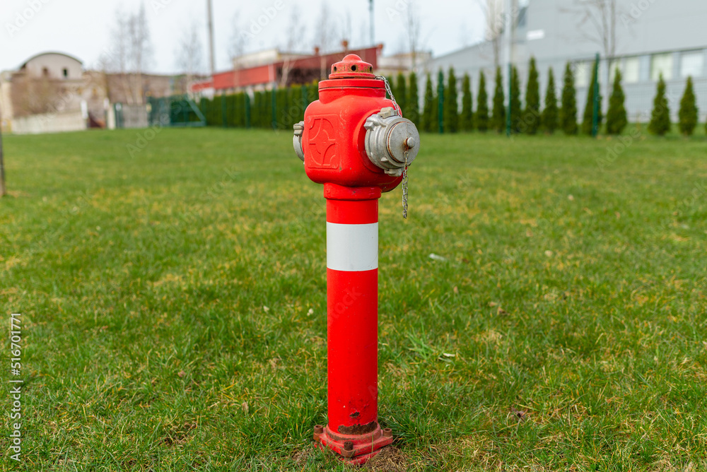 Single red fire hydrant on green lawn,near factory.Autumn,spring,summer day.Copy space. Single red fire hydrant on green lawn,near factory.Autumn,spring,summer day.Copy space.