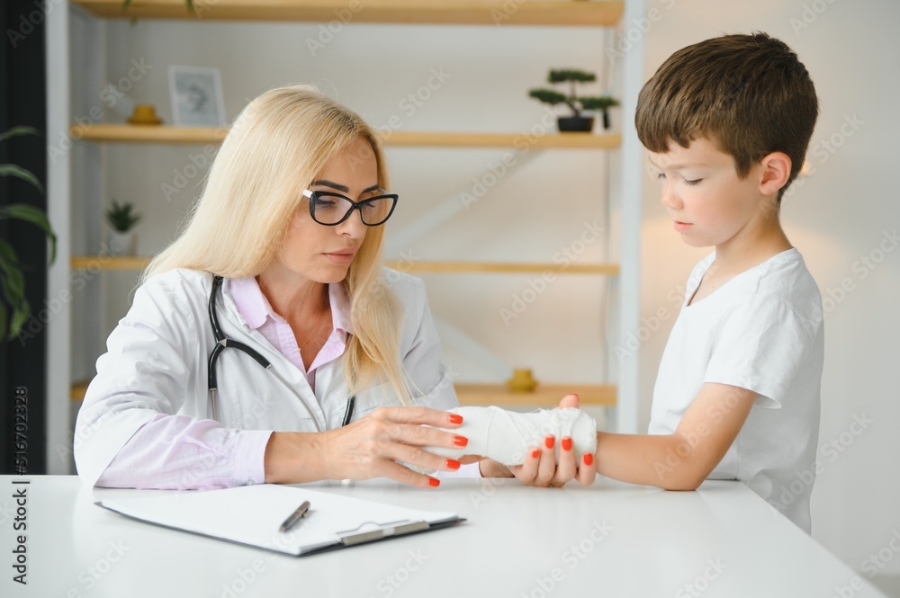 Pediatrician doctor bandaging child's arm. Broken arm in a boy. Pediatrician doctor bandaging child's arm. Broken arm in a boy.