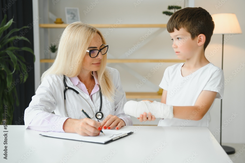 Pediatrician doctor bandaging child's arm. Broken arm in a boy. Pediatrician doctor bandaging child's arm. Broken arm in a boy.