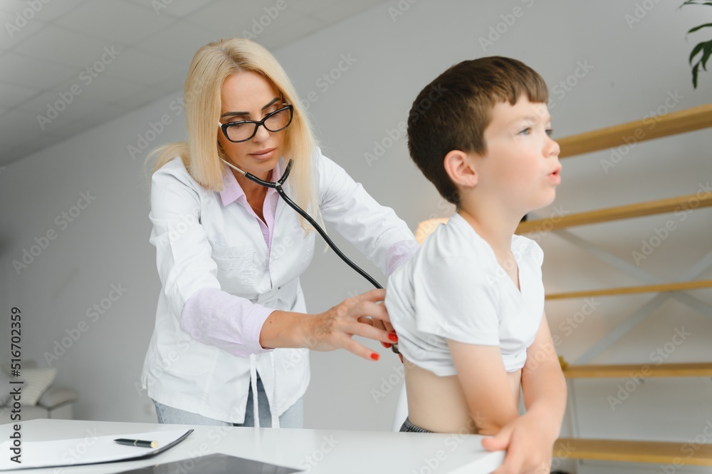 Doctor pediatrician examines child. Female doctor puts a stethoscope to a child's chest and listens to the little boy's heartbeat and lungs. Concept of health care and pediatric medical examination.