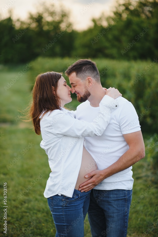 Happy and young pregnant couple hugging in nature Happy and young pregnant couple hugging in nature