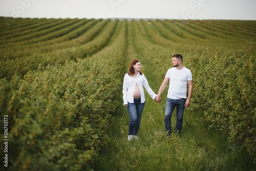 Happy and young pregnant couple hugging in nature