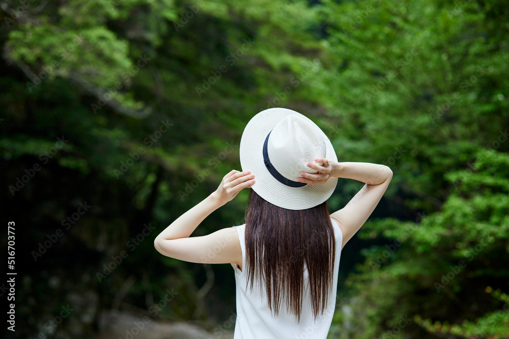 自然の中で佇む女性と麦わら帽子