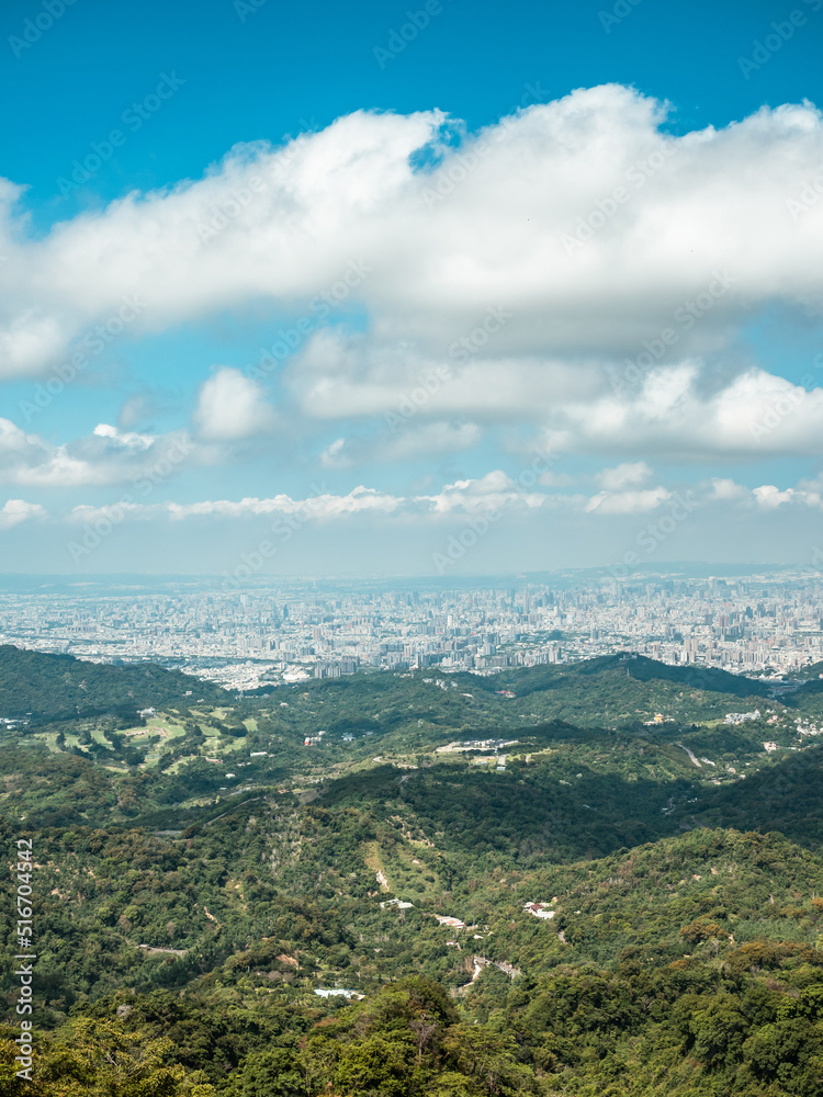 View of city from the beautiful mountain. Blue sky and green meadow in sunset time.