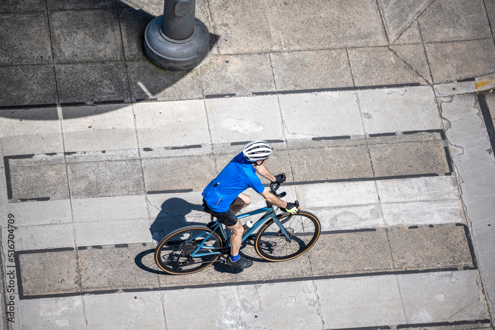 Cyclist in a bicycle outfit as active lifestyle lovers rides along a dedicated bike path on the street of a summer urban city Cyclist in a bicycle outfit as active lifestyle lovers rides along a dedicated bike path on the street of a summer urban city
