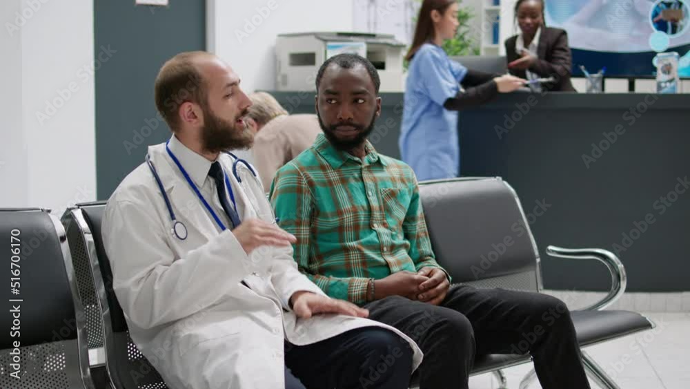 Doctor talking to african american man in hospital reception, doing checkup examination in waiting area lobby. Diverse people chatting about healthcare treatment and diagnosis at facility. Doctor talking to african american man in hospital reception, doing checkup examination in waiting area lobby. Diverse people chatting about healthcare treatment and diagnosis at facility.