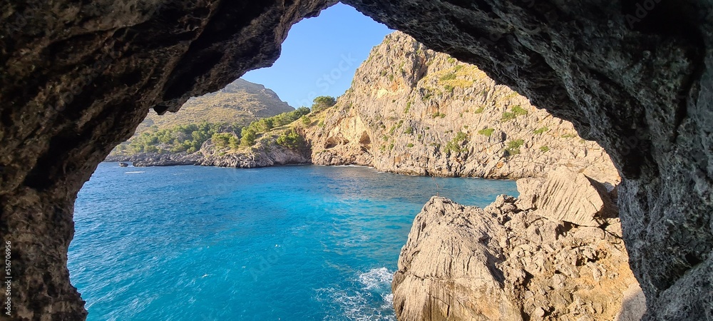 View through a cave window on turquoise waters and mediterranean cliffs