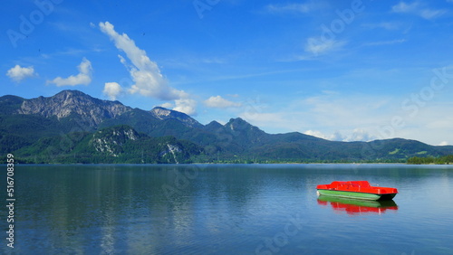 malerischer Blick über Kochelsee in Bayern mit Tretboot Bergen, blauem Himmel und weißen Wolken