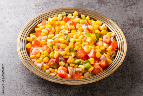 Corn chaat is a super quick snack made with boiled corn, chaat masala, spice powder, onions and tomatoes on a plate closeup on the table. Horizontal