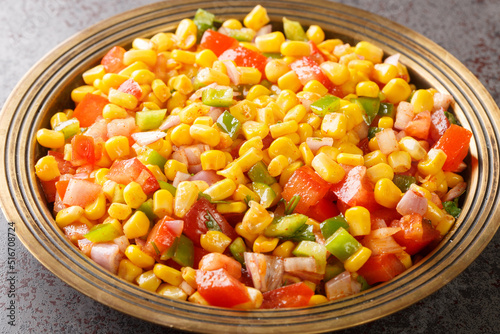 Sweet Corn Chaat is a tangy, spiced and tasty snack made with steamed or boiled sweet corn, onions, tomatoes, herbs and spices. on a plate closeup in the table. Horizontal