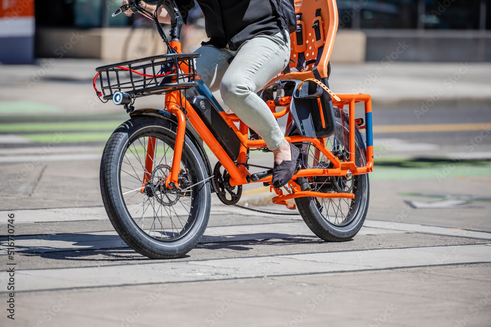 Female cyclist prefers an environmentally friendly mode of transport and moves on a powerful electric bike on the street of an urban city