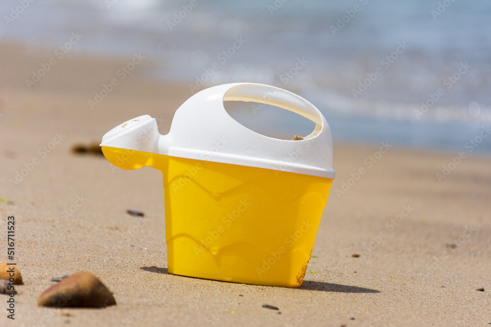 Yellow kid's plastic toy bucket on the beach. Yellow kid's plastic toy bucket on the beach.