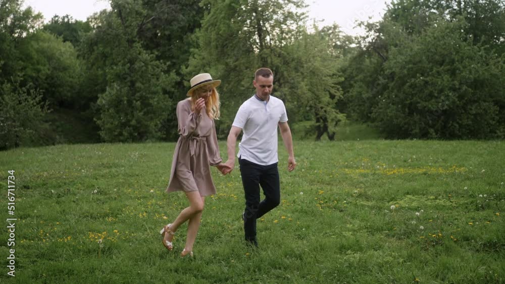 man with a woman blonde in a dress walk on a green field in nature in summer man with a woman blonde in a dress walk on a green field in nature in summer