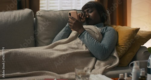 A dark-haired woman is lying in bedroom resting after a severe illness. For several days, the girl has had a cold and has symptoms of fever. There is a flu in the house.