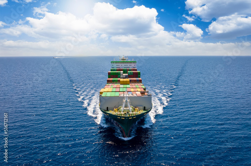Aerial front view of a loaded container cargo vessel traveling over the ocean with good weather