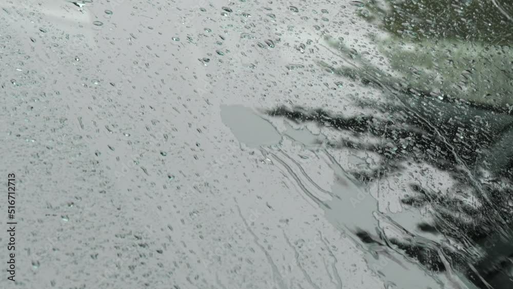bad weather in the summer it is raining water drops on the glass of a car