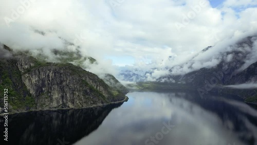 Aerial Flying Over Smooth Reflective Lake Eidfjordvatnet With Clouds Rolling Down Valley. Dolly Forward, Establishing Shot photo