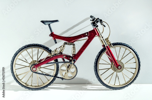 Close-up realistic model of a toy metal full-suspension mountain bike. Miniature bicycle on a white background with text space.