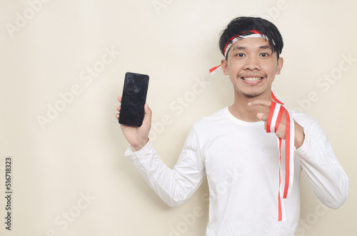 Asian man showing smartphone screen very happy pointing with hand and finger sideways. the concept of independence photo
