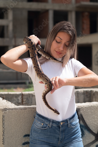 A woman smiling and holding a snake in the urban environment