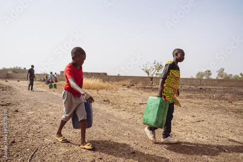 African children fetching water from a village pump; lack of houshold taps and c Fototapet