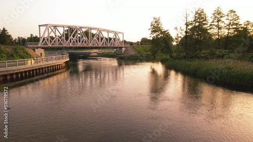 View of the river and railway bridge. Fishing man. Slow drone flight low over the water during sunset. Pisa River, Masuria, Pisz, Poland photo
