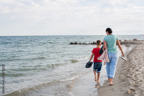 boy and mother walking along the sea beach