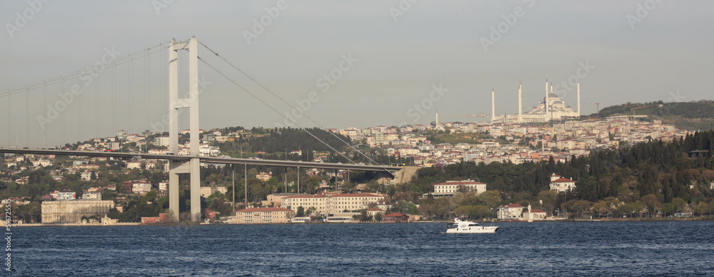 Istanbul, Turkey - April 2022: Stunning view over Bosphorus Bridge and a boat near it from the cruise ship in the evening. Haze and fog