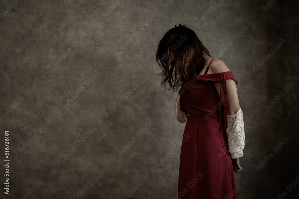 Woman in red dress standing in a dark room. Concept. Horror, scary, ugly.