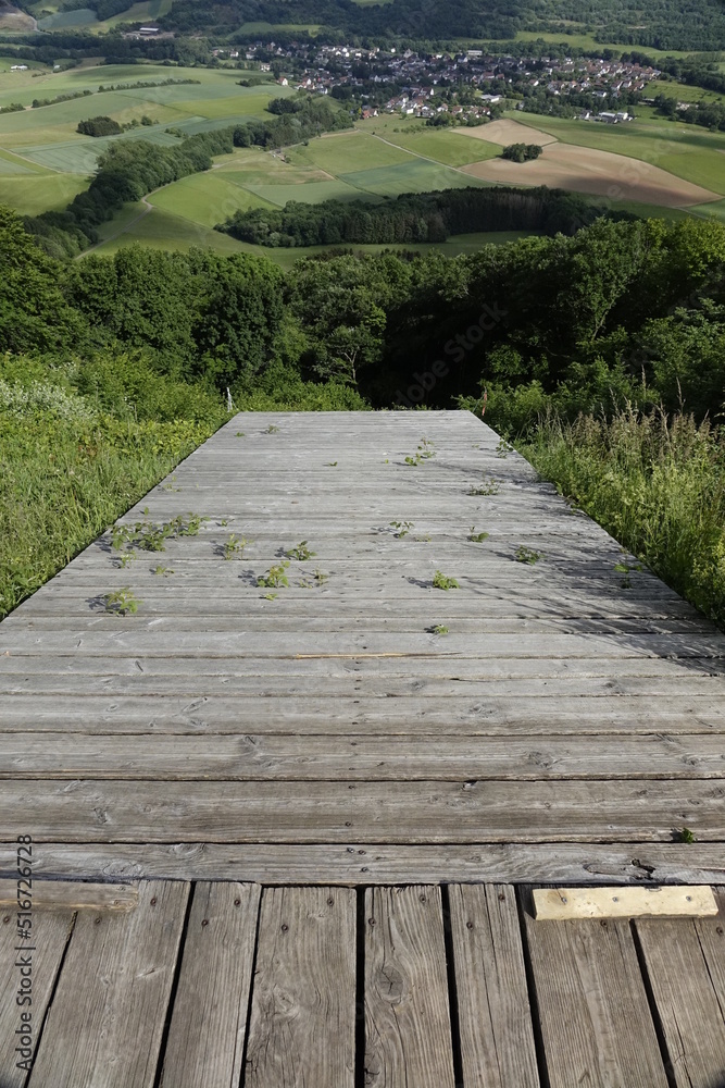 Fototapeta premium Looking down into the abyss from a steep wooden paragliding and hang-gliding start, sunny spring day, concept: thrill, adventure, courage, adrenaline (vertical), Pfeffelbach, Kusel, RLP, Germany