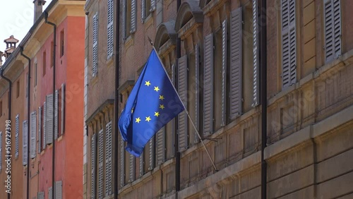 The flag of the European Union waving alone against the backdrop of a gray building.