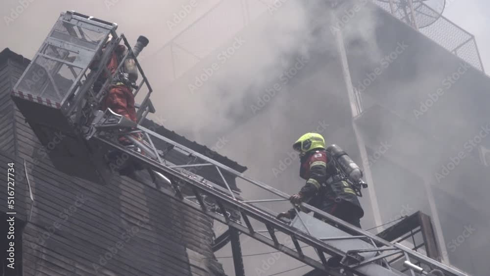 Firefighters climbing Ladder to extinguish the fire burning building ...