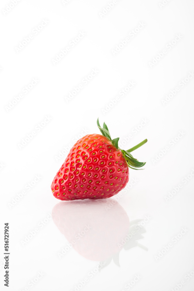 Fresh organic strawberries on a white reflective surface. Close up shot.