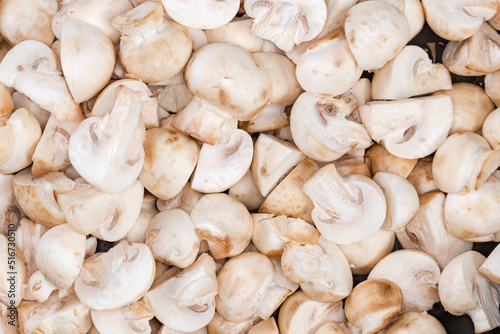 Background of raw sliced button mushrooms, top view close-up