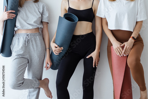 A group of young sports girls standing against a wall. time to recuperate, waiting for the start of the lesson in the loft studio, close-up. Healthy lifestyle concept