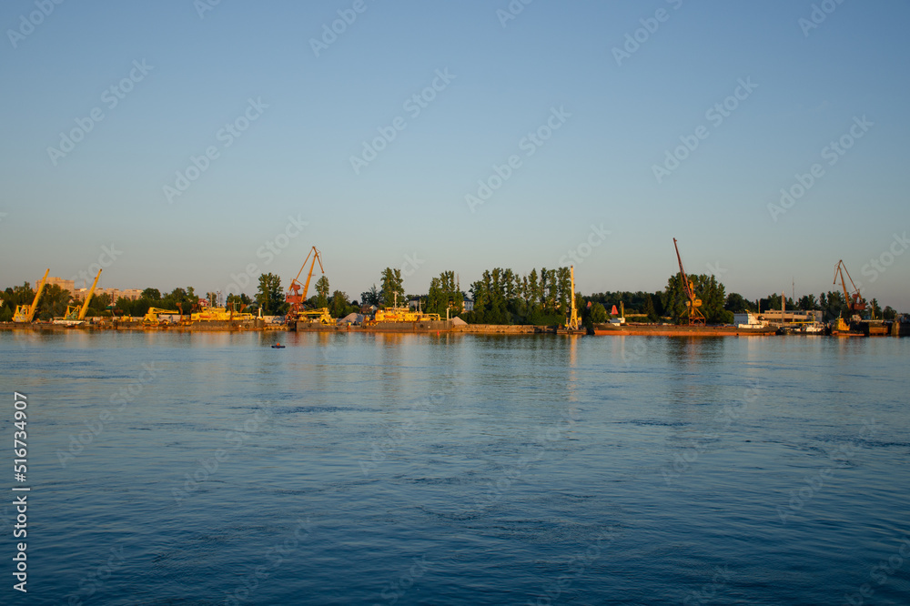 Trading river port and cargo cranes against the background of blue water and sky
