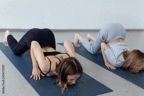 young flexible girl doing yoga and gymnastics indoor gymnastics, flexibility and stretching assana lying backbend photo