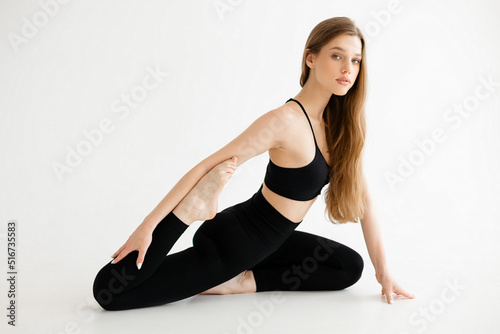Beautiful sports girl doing stretching on a white background