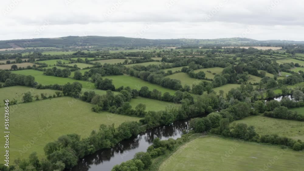 Aerial rises over small river running through lush green pasture land Aerial rises over small river running through lush green pasture land