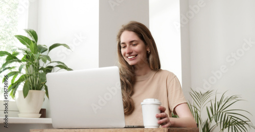 Young woman freelancer or student using laptop computer at home. Business woman working and smiling in office. Work or study online, freelance, business, distance education concept