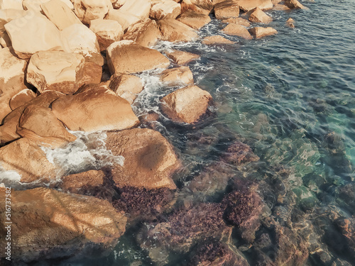 Seashore with large boulders. Mediterranean Sea coast, Cyprus. Rocky shore with clear blue water.
