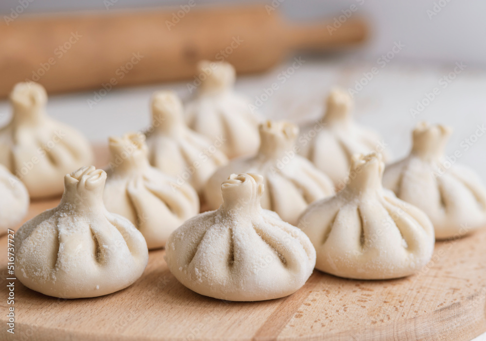Famous georgian dish meat khinkali uncooked on cutting board with copy space Famous georgian dish meat khinkali uncooked on cutting board with copy space