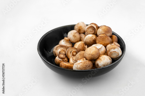 mushrooms champignon in bowl on white background