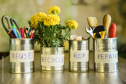 Using cans on different purposes at domestic life. Stationery, home flower, tools, organic waste in tin cans standing in row on blurred background. Upcycling, Environment conservation. Reducing waste photo