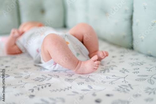 Small children's feet are lying on the bedspread. Cute newborn concept