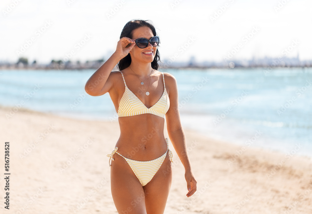 people, summer and swimwear concept - happy smiling young woman in bikini swimsuit and sunglasses on beach people, summer and swimwear concept - happy smiling young woman in bikini swimsuit and sunglasses on beach