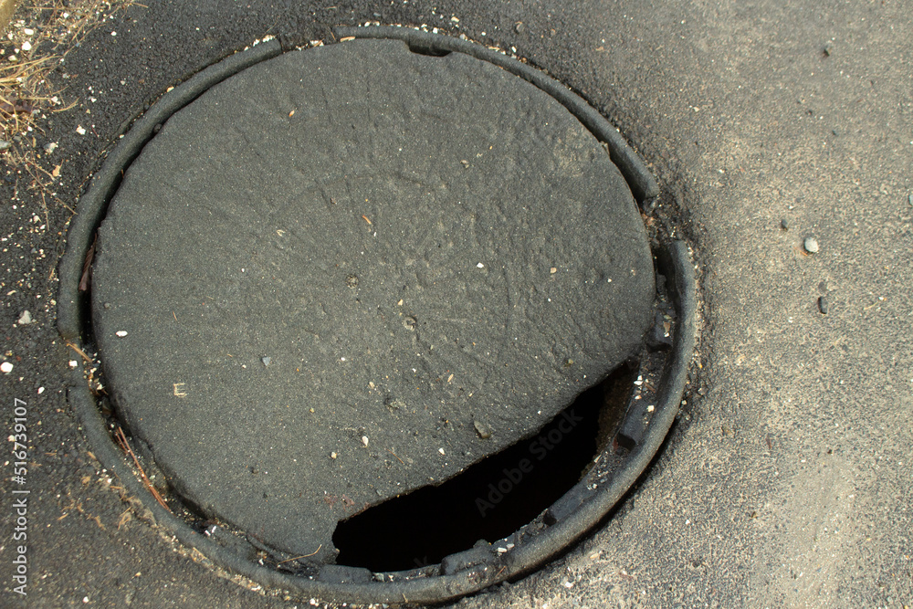 Hole in asphalt. Hatch in ground. Broken cover. Dangerous place on road.  Stock Photo | Adobe Stock