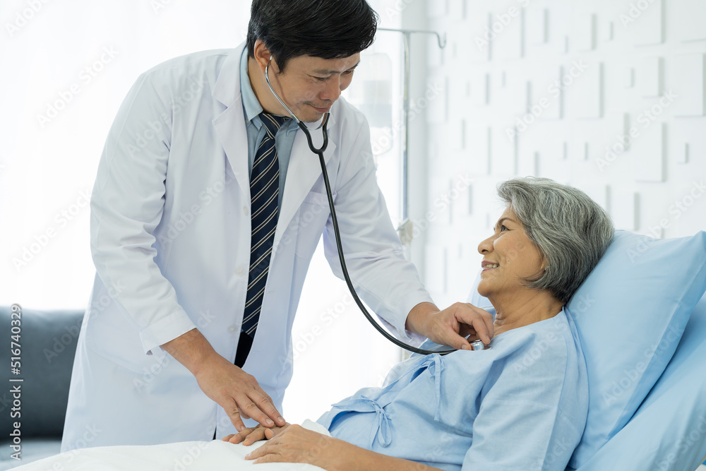 Obraz premium Doctor and patient in the patient room at hospital. Male doctor using stethoscope examining elderly woman patient’s heartbeat. Male doctor visiting and checking female patient. Health care concept