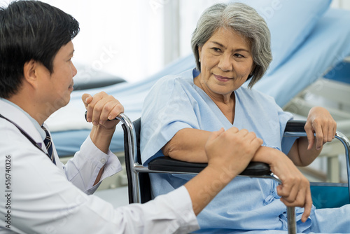 Happy doctor taking care elderly asian woman on wheelchair at the hospital. People and health care concept