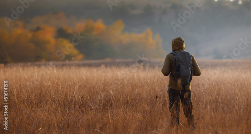 Young handsome man posing in autumn nature. guy standing in field over sunset. Goals, hopes and aspirations concept. enjoying nature view. Hiking and trekking. Concept Adventure and Travel © YURII Seleznov
